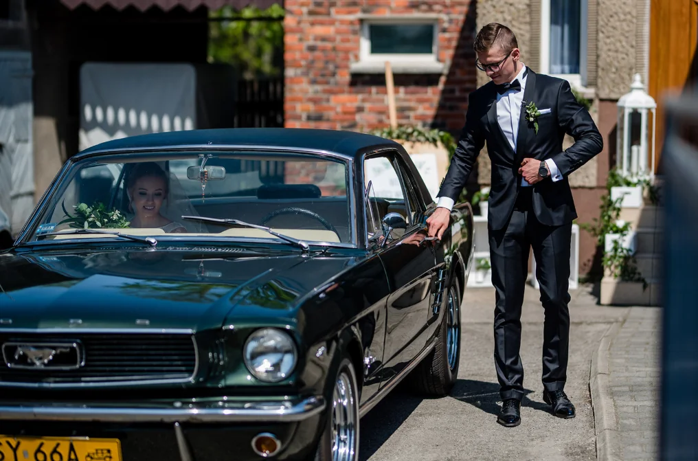 Pan młody przy zabytkowym Mustangu przed ceremonią